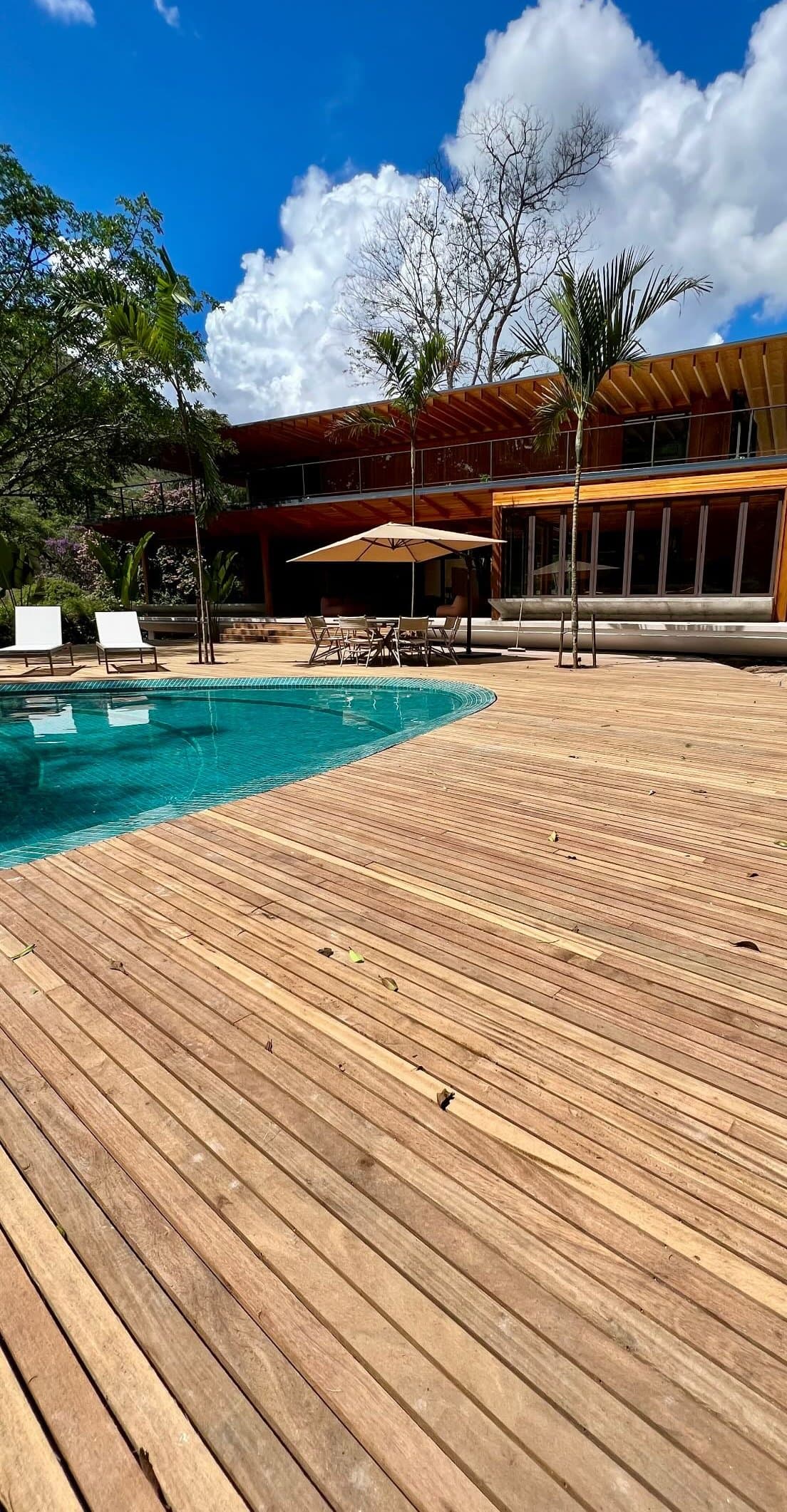 Fachada de residência de alto padrão em Nogueira, Itaipava, vista do deck de madeira junto à piscina, obra da Arte Construir