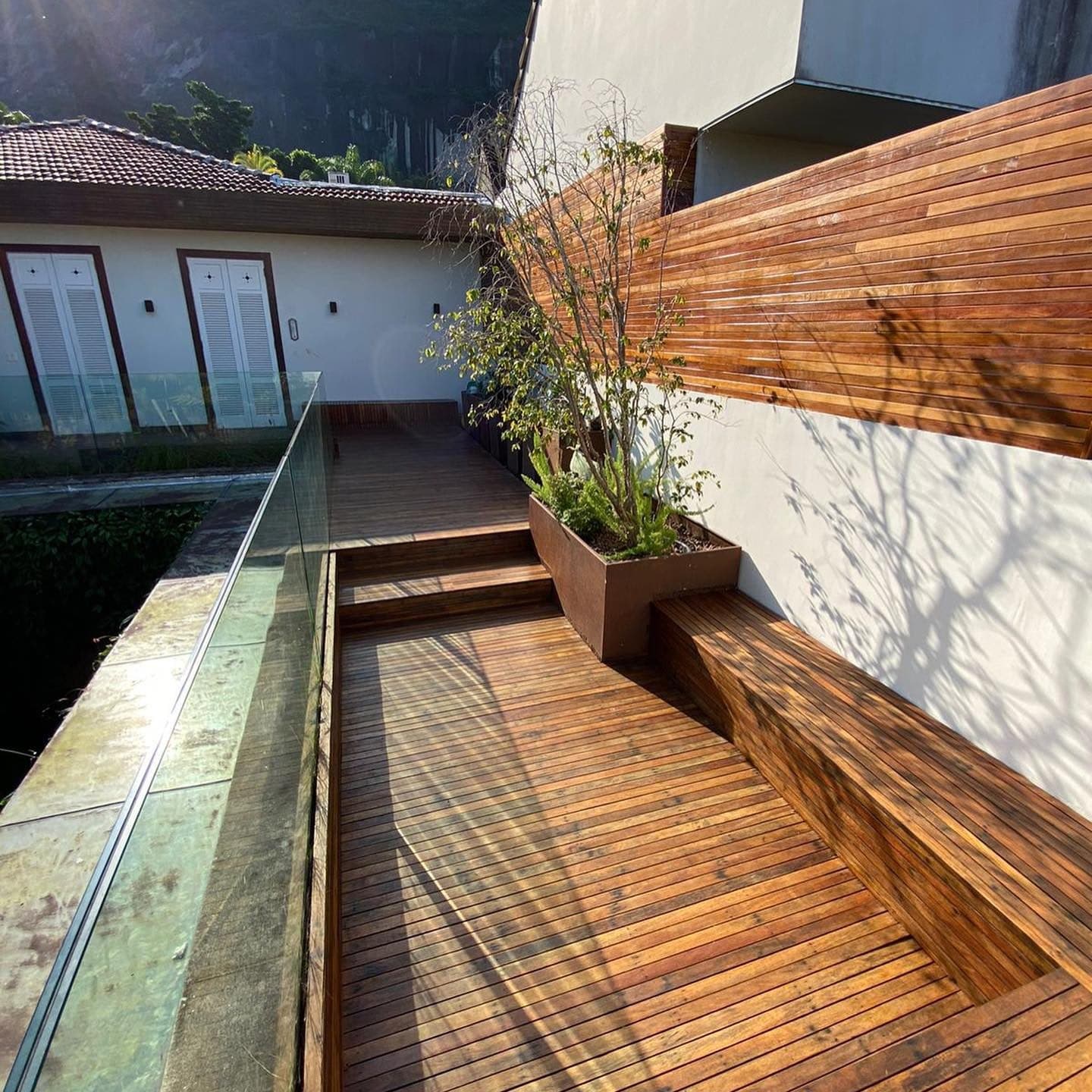 Deck de ipê com banco, vaso e painel ripado