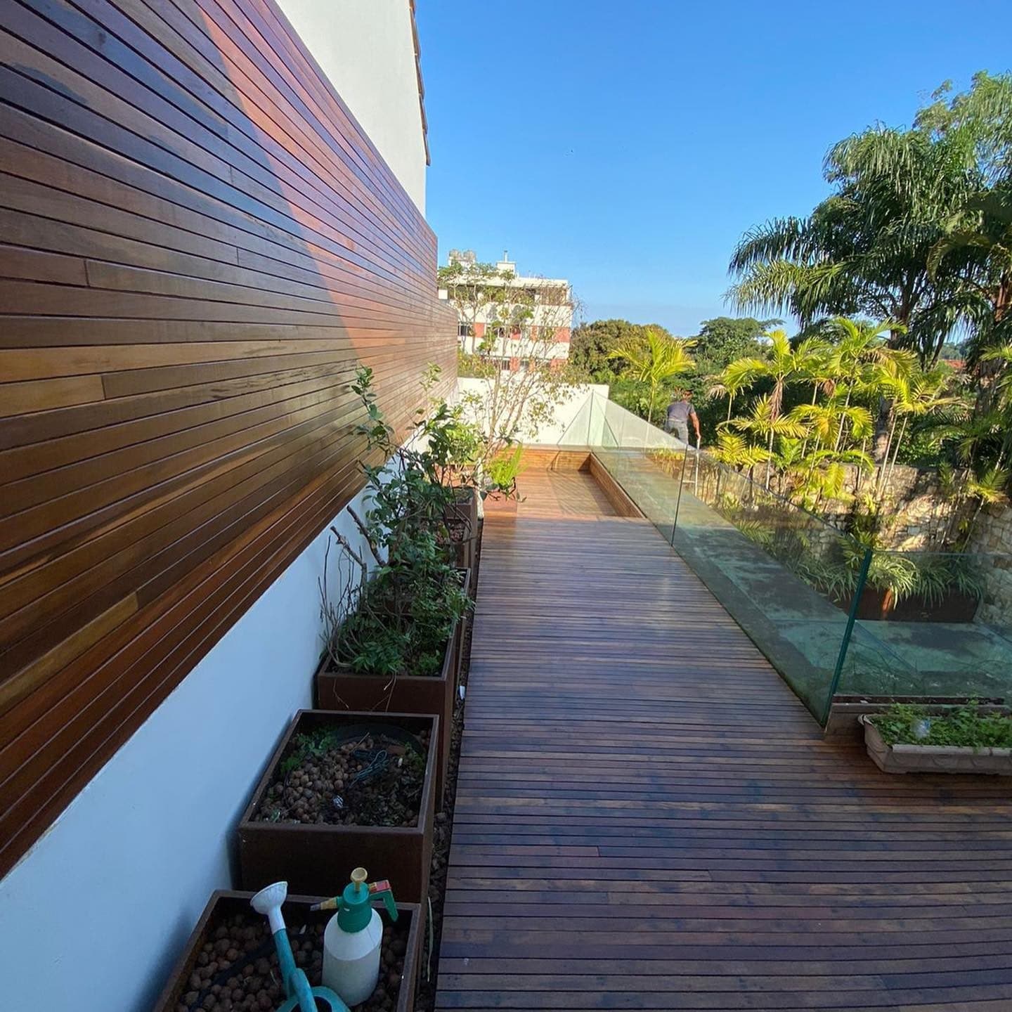 Deck estreito de ipê ao lado de painel ripado e jardineiras