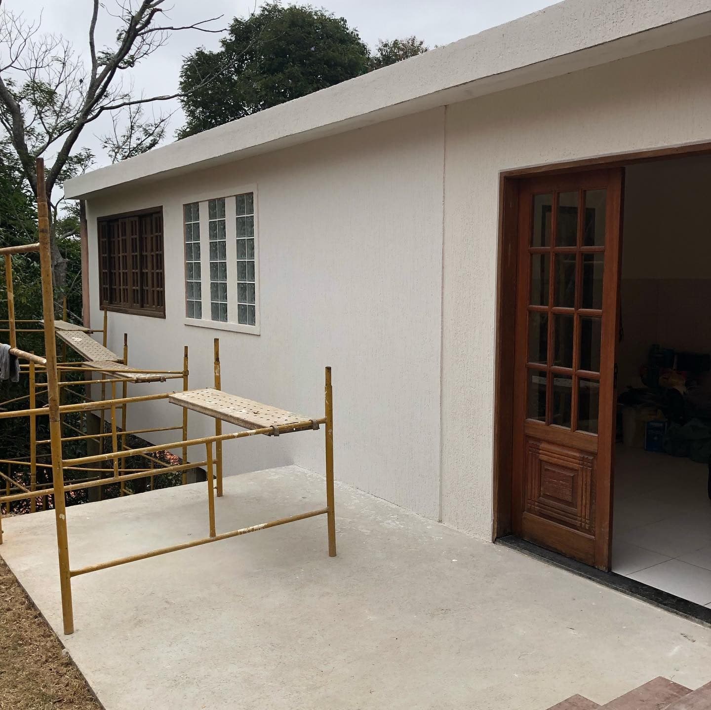 Casa pintada de claro com portas de madeira, reforma concluída