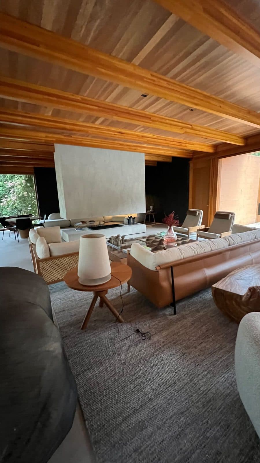 Sala ampla de casa de alto padrão com vigas de madeira aparentes