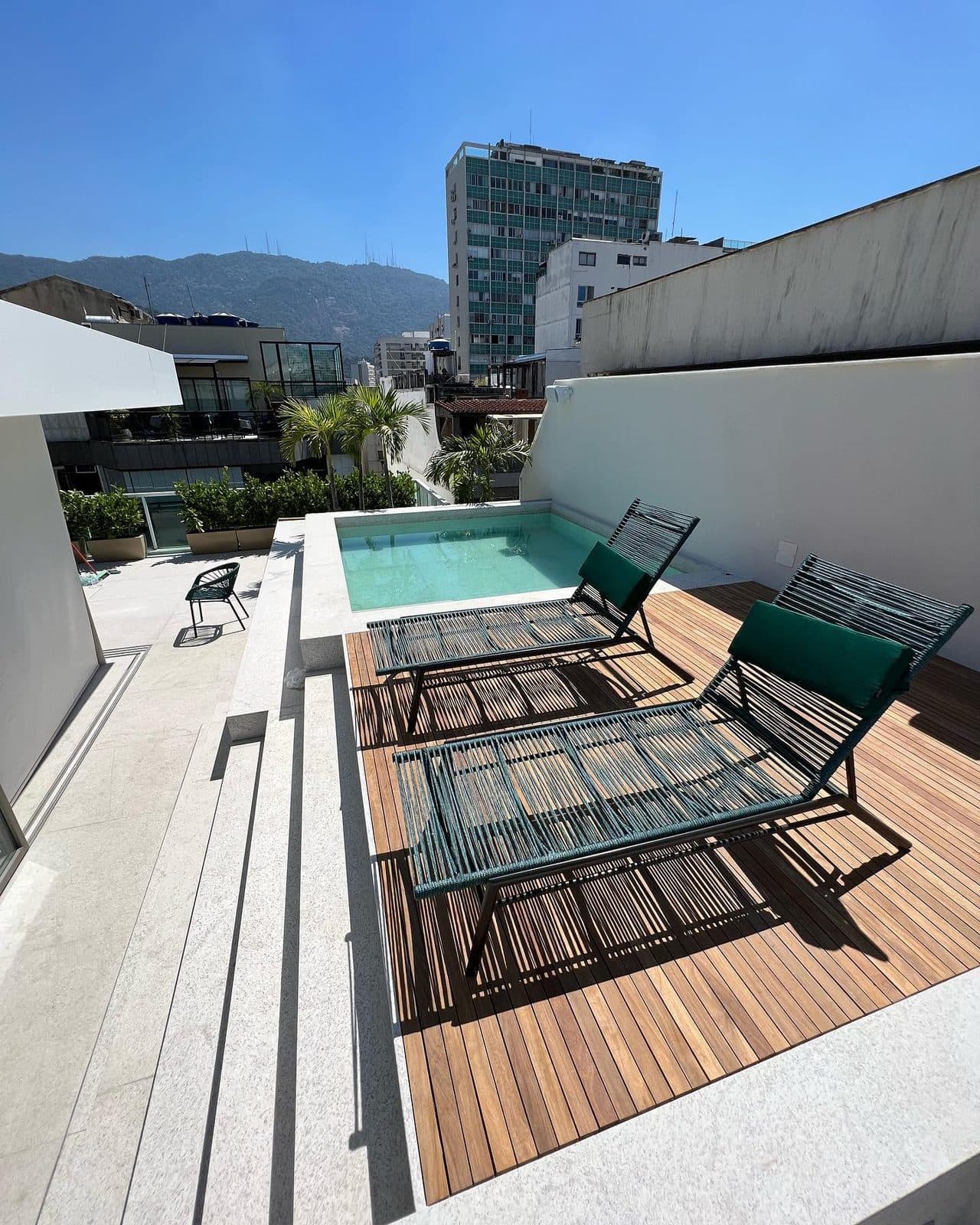 Deck de madeira natural com espreguiçadeiras e piscina em cobertura