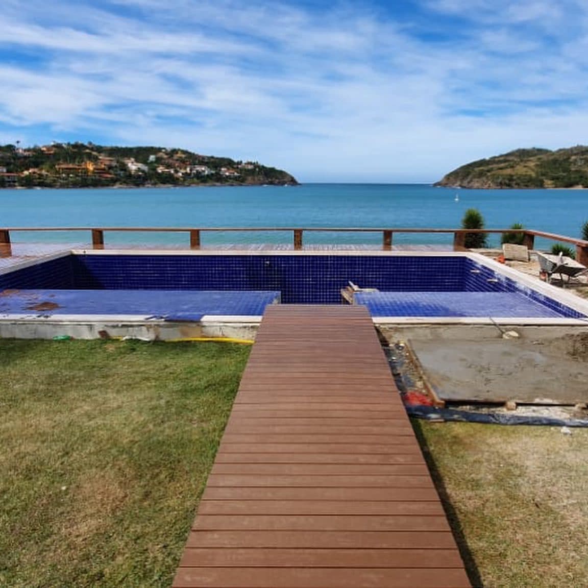 Passarela de deck sobre gramado até piscina e mar, casa de praia