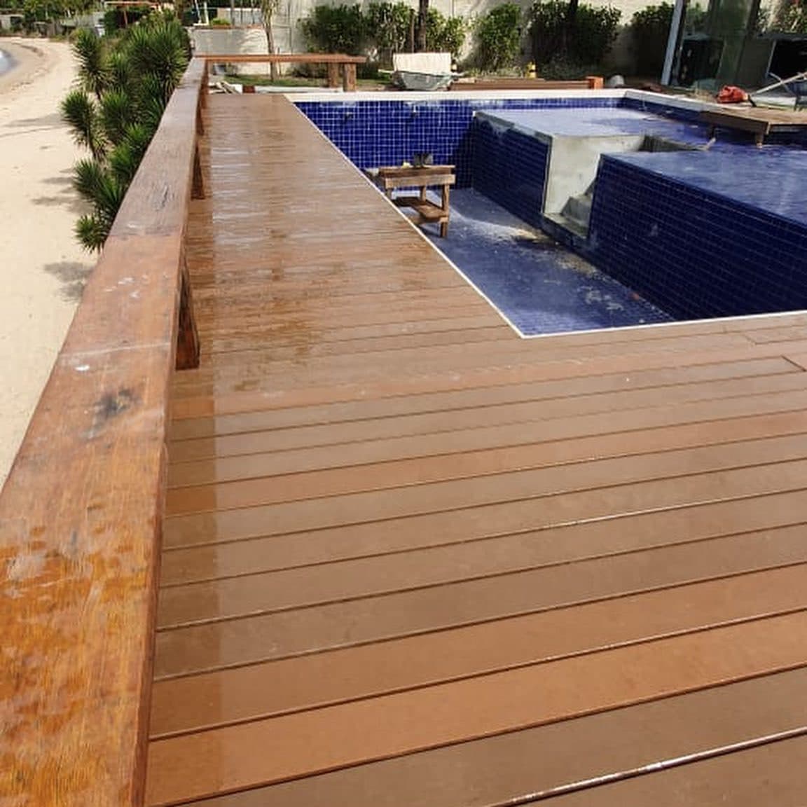 Deck em L ao redor da piscina azul com banco