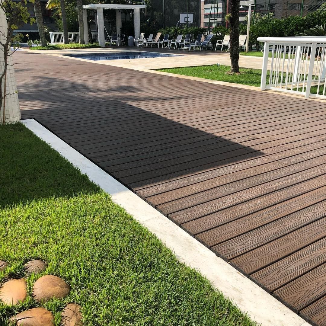 Deck de madeira plástica escura junto à piscina de hotel