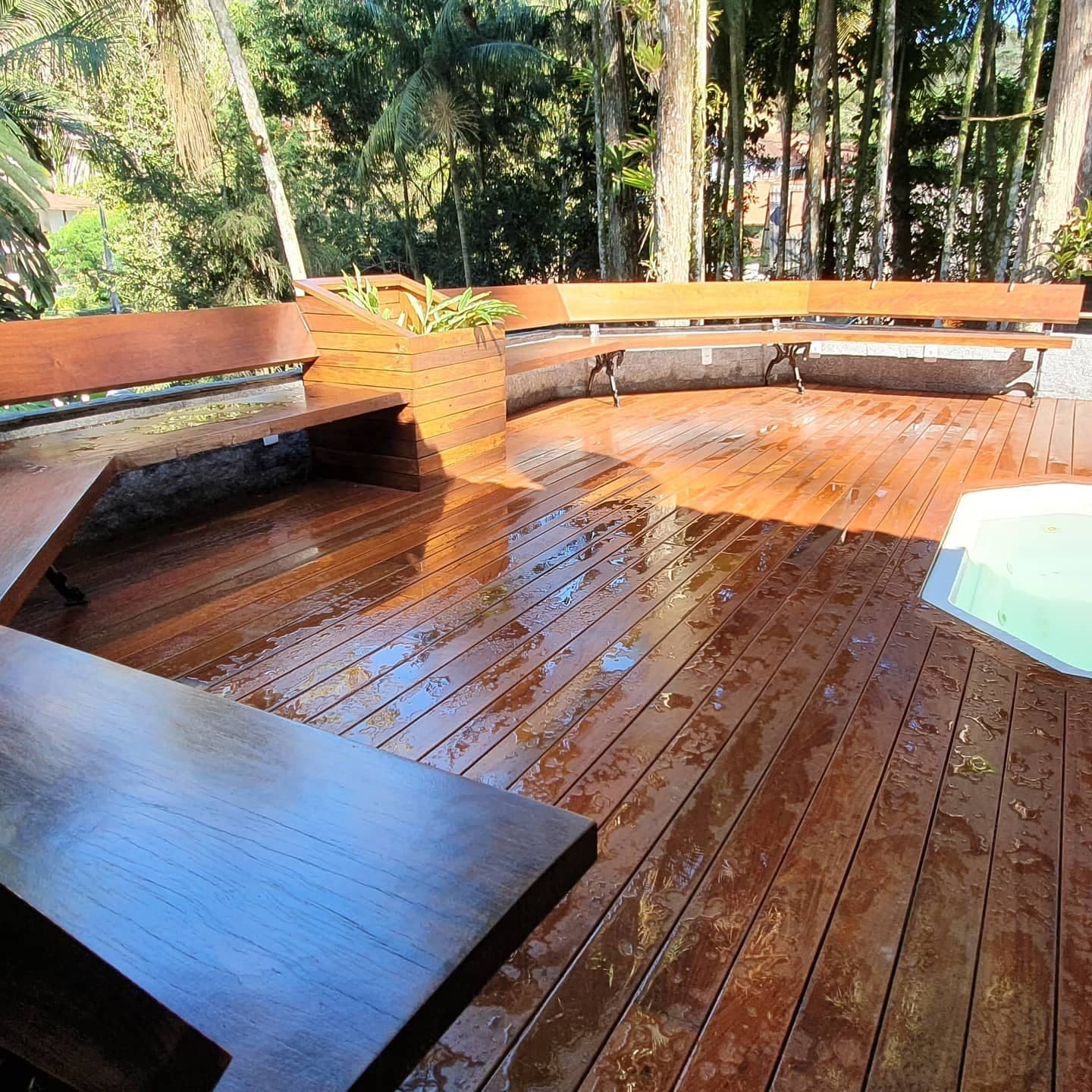 Deck de ipê tabaco com bancos embutidos e jardineira, mata ao fundo