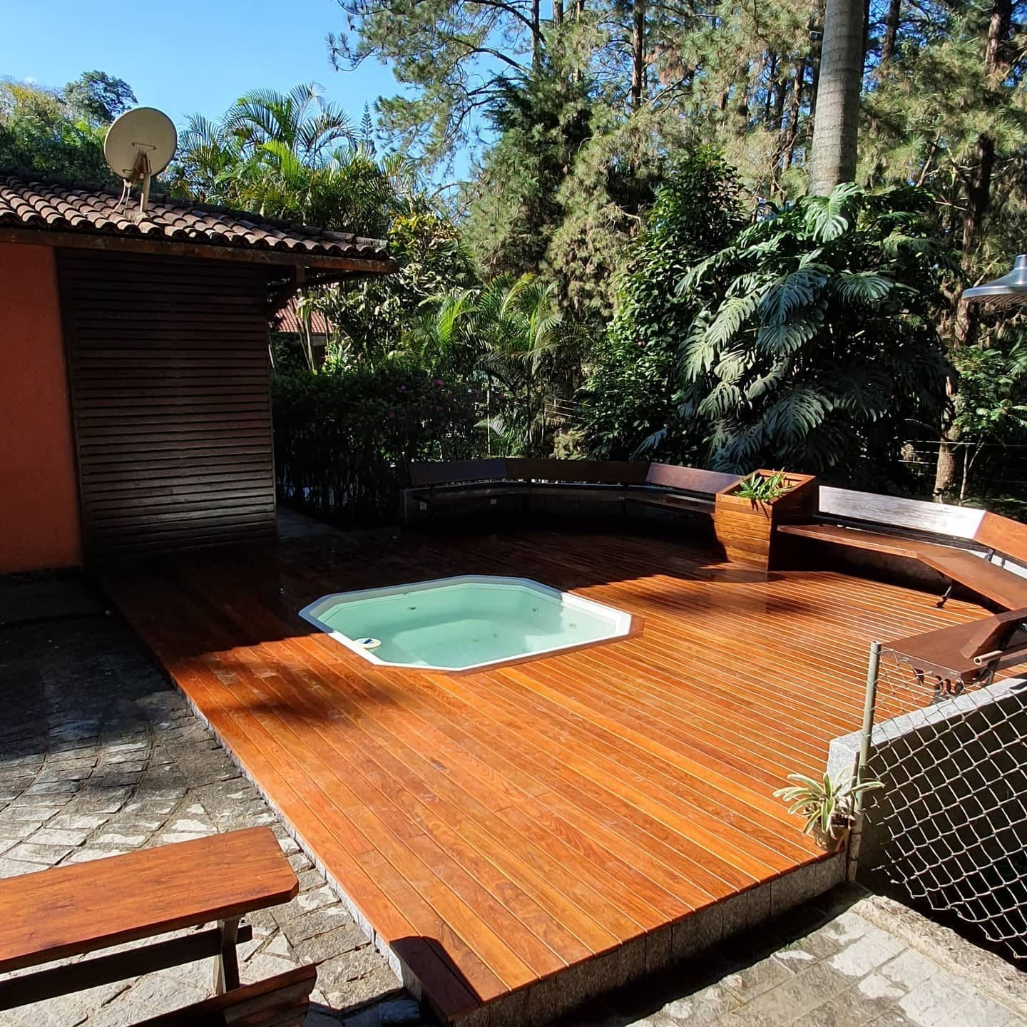 Deck de ipê tabaco com spa redondo e casa de telhas ao fundo
