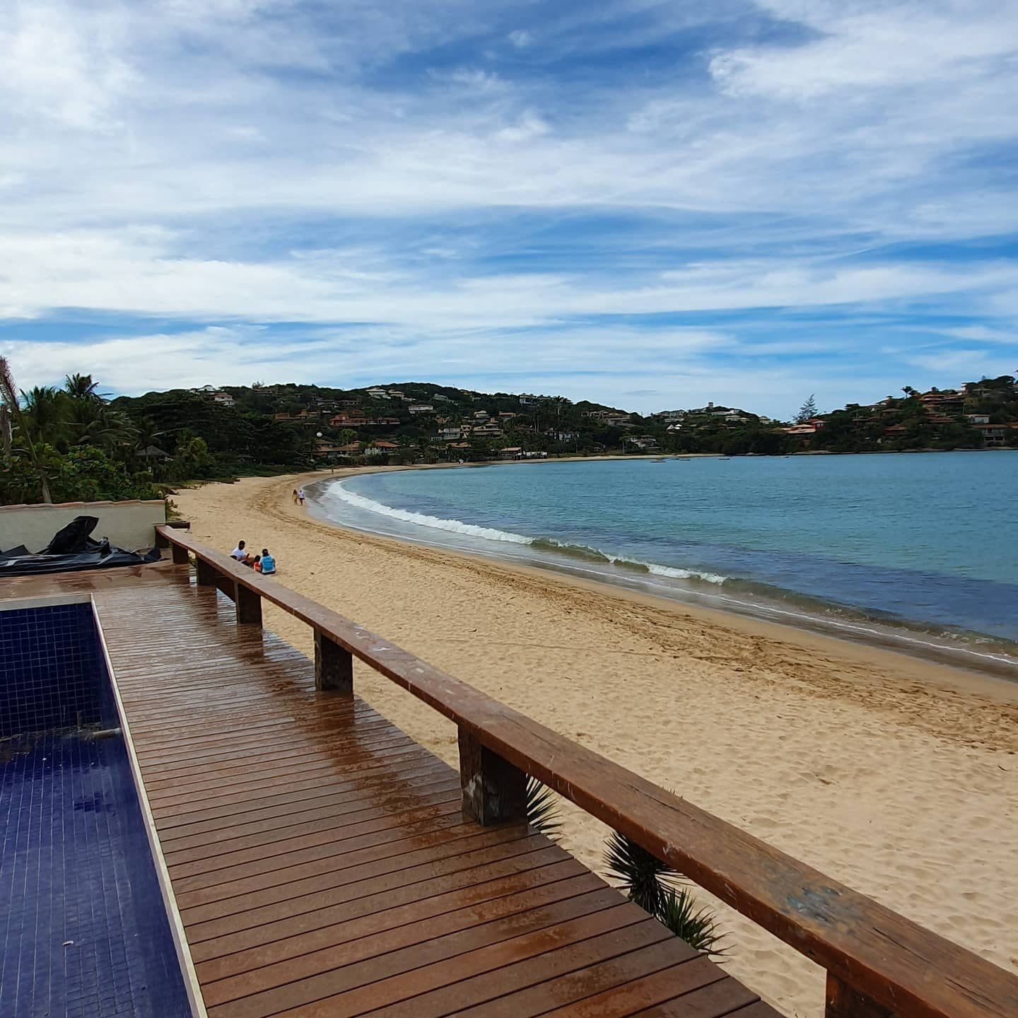 Deck com banco e guarda-corpo de frente para a praia e a piscina