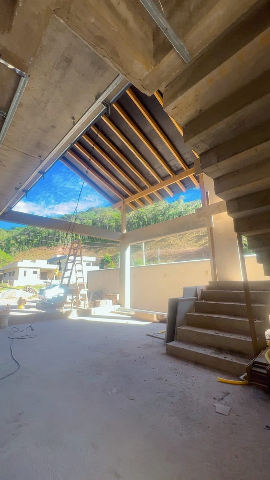 Pé-direito duplo com escada de concreto, forro ripado de madeira e vista