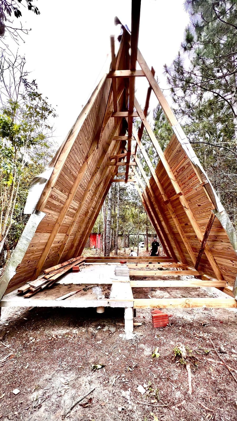 Vista interna do esqueleto de chalé A-frame, tábuas e caibros