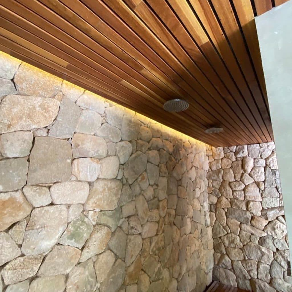 Forro de cumaru e parede de pedra com iluminação de LED