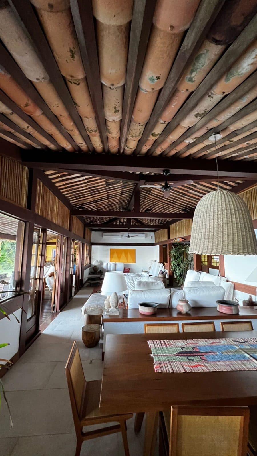 Interior rústico com madeira aparente, forro de bambu e sala ampla
