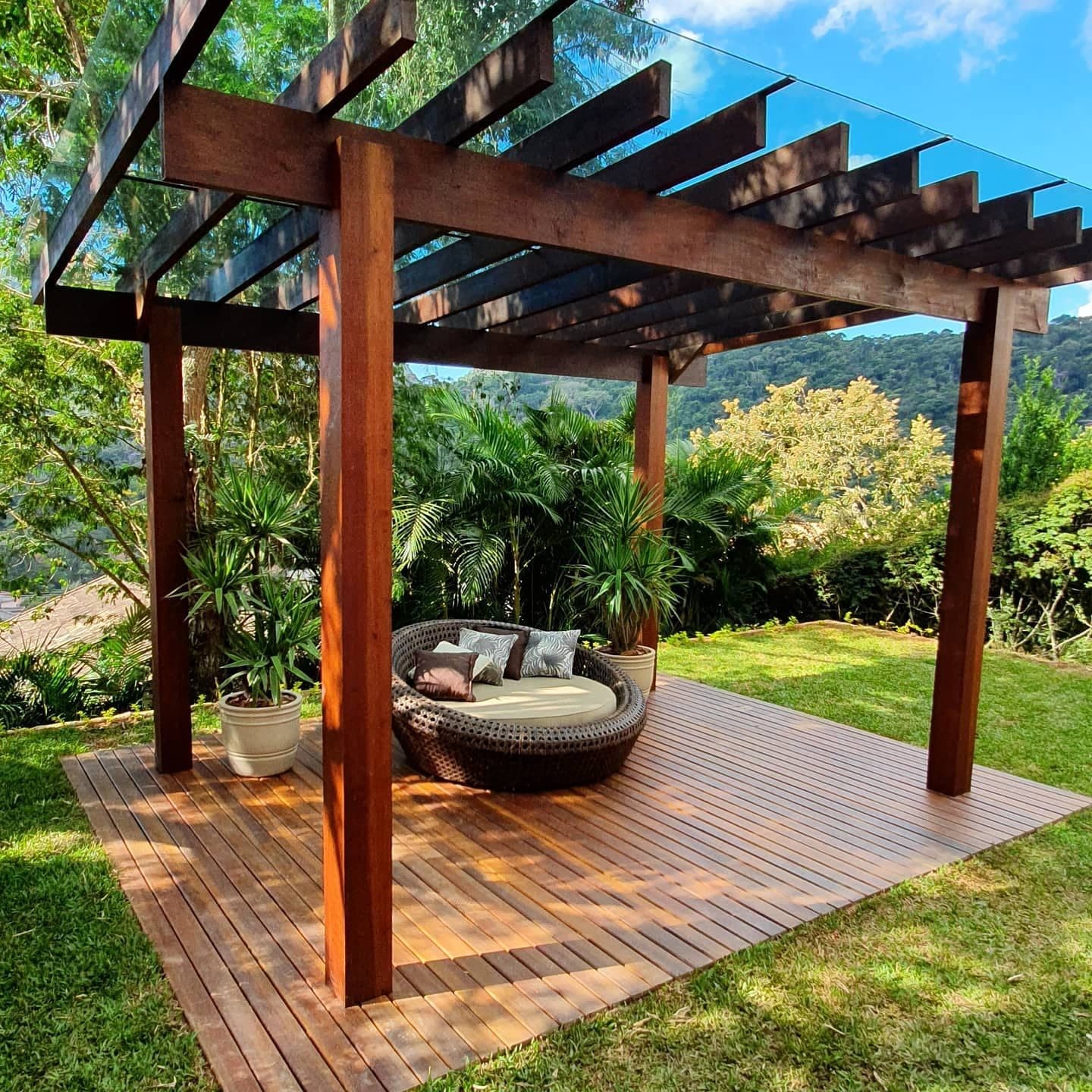 Pergolado de massaranduba com cobertura de vidro e deck, jardim tropical