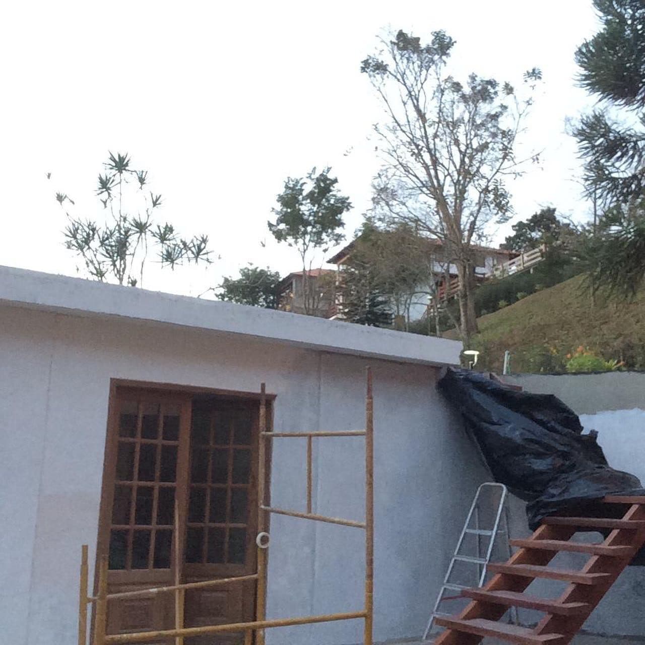 Casa com reboco novo, andaime e portas de madeira, durante a reforma